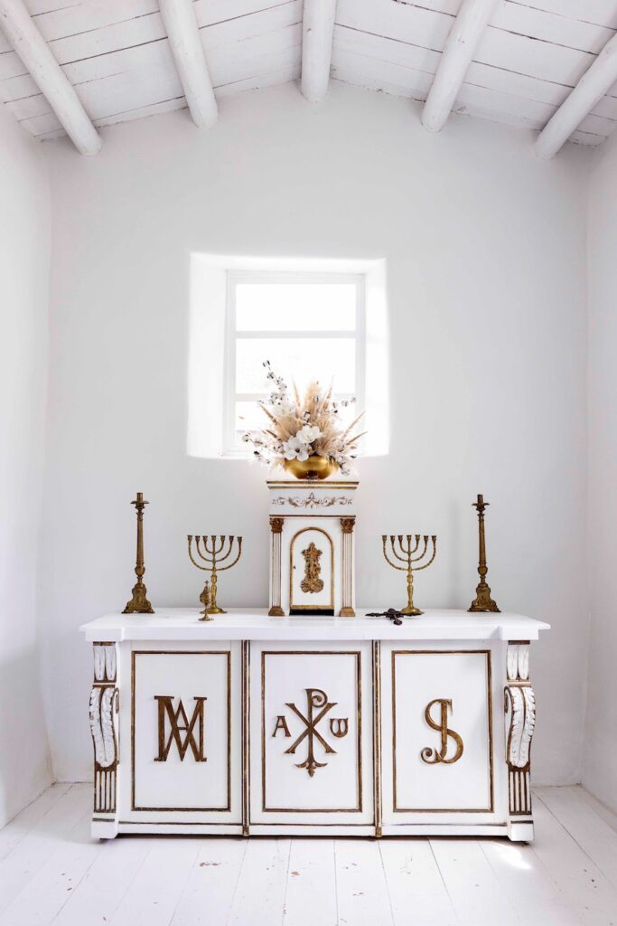 Inside view of a white room with a white dresser and white candles with gold accents